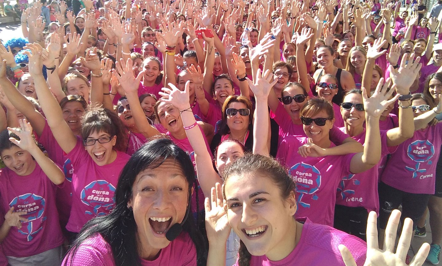 Grup de dones amb samarretes roses aixecant les mans, Cursa de la Dona